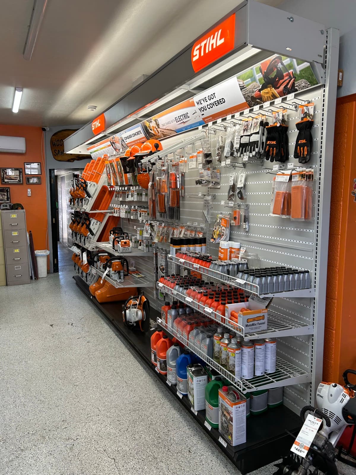 STIHL accessories aisle with gloves, bar oil, chains, files, and protective gear on shelving