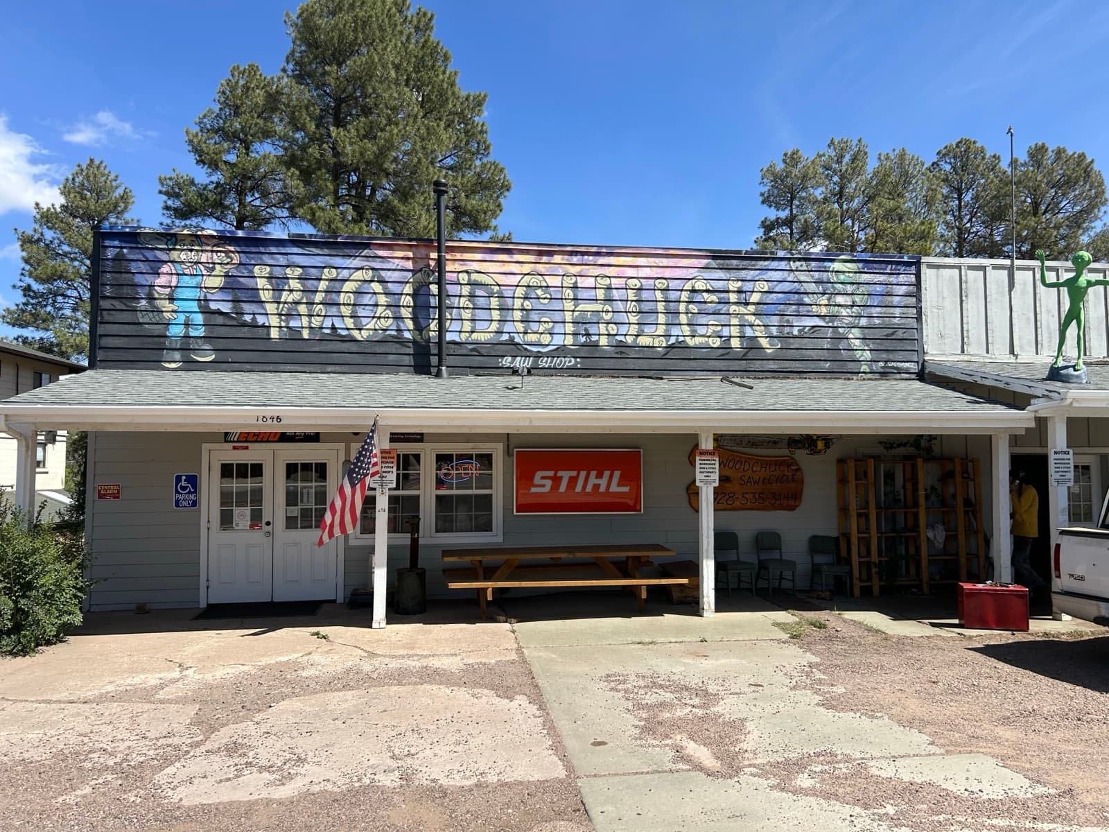 Woodchuck Saw Shop storefront in Heber-Overgaard, Arizona — hand-painted sign over the porch, STIHL banner, ladders and equipment visible through the open shop door